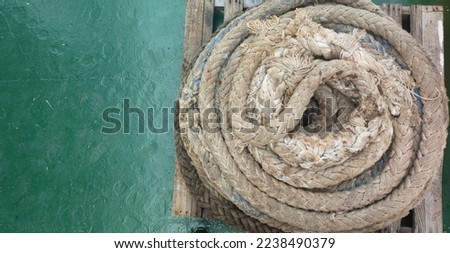 Top veiw large piles of ship's ropes rolled in circles rested on wooden pallets on the ship's green deck in port