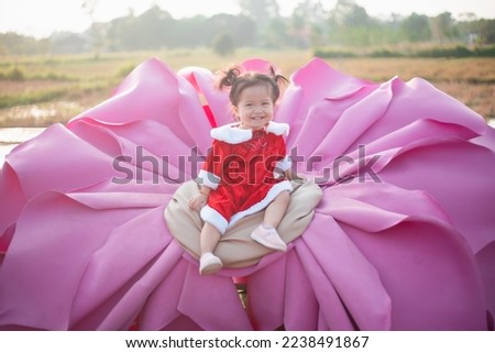 Pretty little kid girl wears Christmas dress playing snow in the park. beautiful baby girl feeling happy on blur background. Christmas day and happy new years concept. Copy space for text.