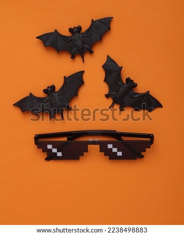 Bats with pixel sunglasses on an orange background. Halloween concept