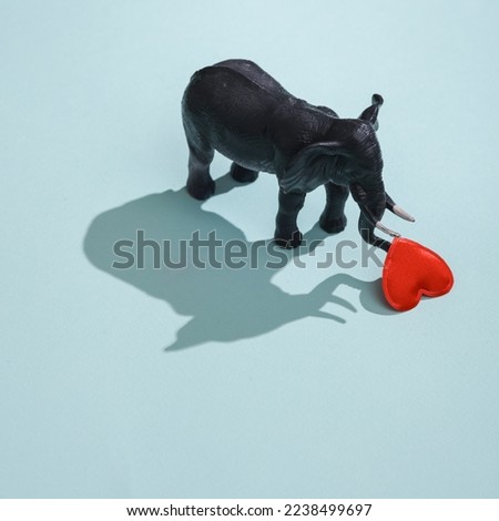 Plastic elephant with heart on blue background. Love concept, valentine's day, february 14th celebration, creative layout