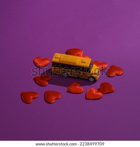 Toy school bus with hearts on a purple background. Love concept, valentine's day, february 14th celebration, creative layout. Back to school