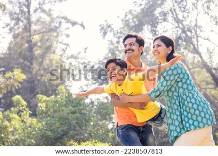 Cheerful parents assisting son in flying at park.