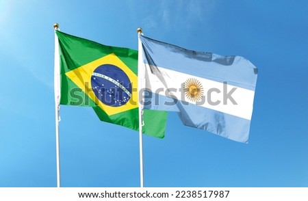 Brazil flag with Argentina flag on cloudy sky. waving in the sky Royalty-Free Stock Photo #2238517987