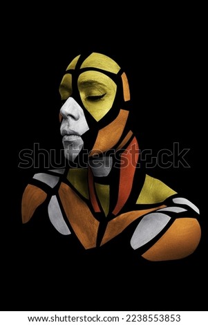 Portrait of a human with creative art makeup posing in the studio. Shape of colored polygons on beautiful face. Parts of face isolated on black background.