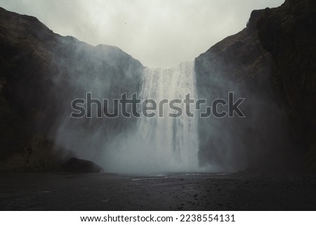 Skogafoss waterfall landscape photo. Iceland nature. Beautiful nature scenery photography with grey sky on background. Idyllic scene. High quality picture for wallpaper, travel blog, magazine, article