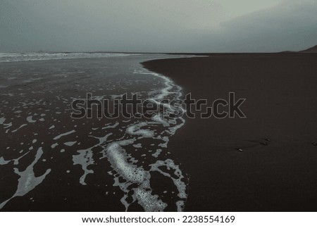 Wet surfline of black beach landscape photo. Beautiful nature scenery photography with gloomy sky on background. Idyllic scene. High quality picture for wallpaper, travel blog, magazine, article