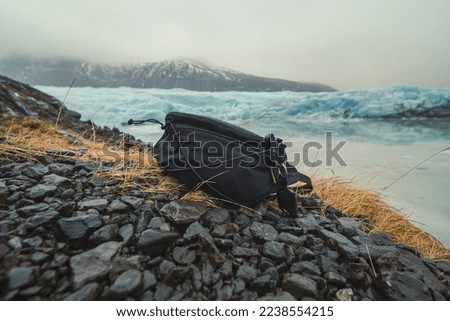 Close up container for camera on ground concept photo. Cameraman equipment. Front view photography with ice mountains on background. High quality picture for wallpaper, travel blog, magazine, article