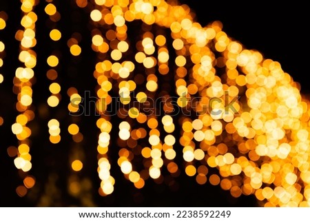 Festive bright blurred golden background. On Christmas black curtain, yellow bokeh lights are shining out of focus. Blank for postcards, place for text. Disco effect. Macro concept. Sparkling lamps