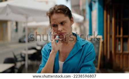 Young woman standing with doubt expression at street