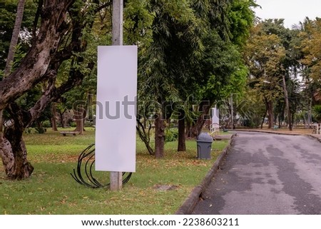 Empty white sign next to a road in a park