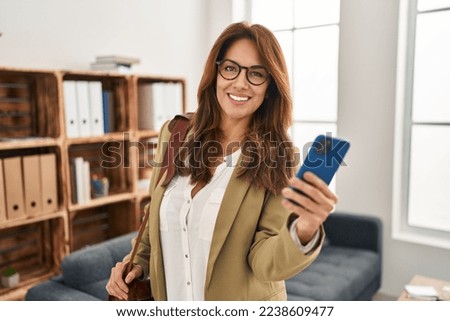 Young latin woman smiling confident using smartphone at clinic