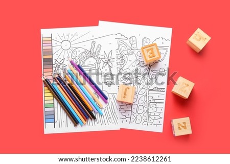 Coloring pages, pencils and cubes on red background