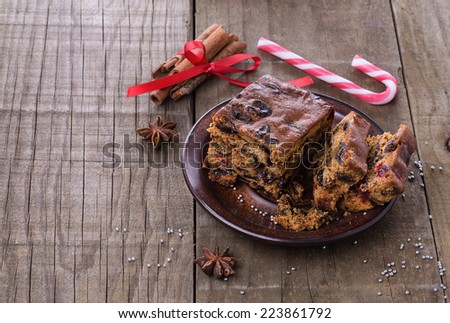 Christmas fruit cake in a ceramic plate over rustic wooden background