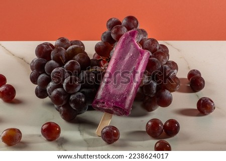 Grape ice cream on bunches of grapes on white background.