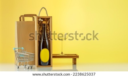 Eco friendly wine shop, wine bar winery or wine delivery concept. Mockup of bottle with champaign in a wooden box with wine glass, paper bag,  shopping cart on yellow sunny background with copy space