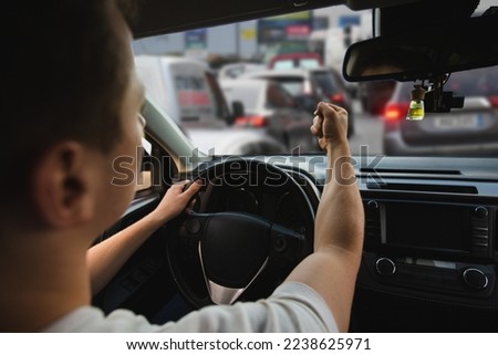 Novice driver sitting in his car behind the wheel shaking his fist threatens another motorist. Bad and aggressive behavior on road concept. Royalty-Free Stock Photo #2238625971