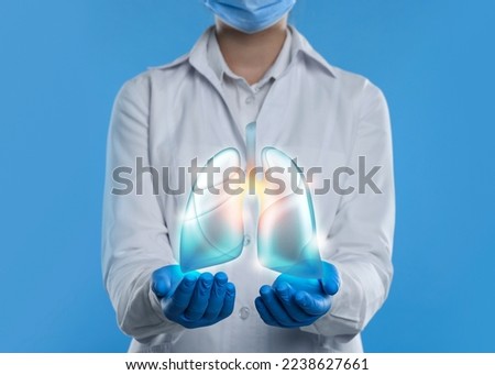 Doctor demonstrating digital image of human lungs on light blue background, closeup Royalty-Free Stock Photo #2238627661