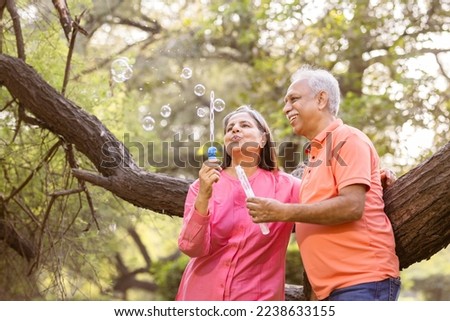 Active senior couple having fun blowing bubbles at park. Royalty-Free Stock Photo #2238633155