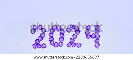 New Year 2023 inscription from glass hearts on a violet background. Pantone color 2023. Idea and creativity. Valentine's Day. Christmas with loved ones. Horizontally, banner. High quality photo