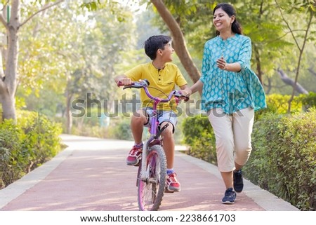 Mother teaching son to ride bicycle.