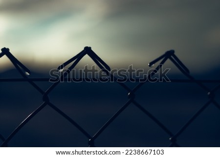 Moody dark photo of water drops on wire fence.