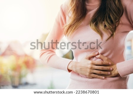 Asian young female suffers from stomachache after eating spoiled food, Abdominal pain from menstrual cramps, Sick woman unhappy having stomach ache digestive problem at home Royalty-Free Stock Photo #2238670801