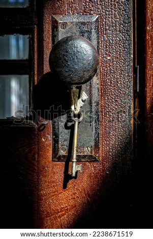 A key hangs on a door handle in a shaft of light 