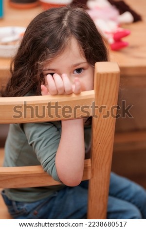 cute little girl making faces for the camera while sitting at a table