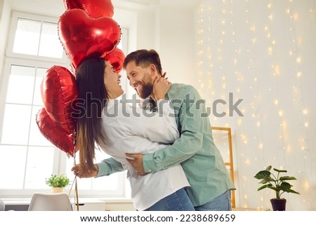 Happy, cheerful couple in love celebrating St Valentine's Day. Joyful, positive young man and woman enjoying Saint Valentine's Day, hugging, dancing with red heart shaped balloons, having fun together Royalty-Free Stock Photo #2238689659