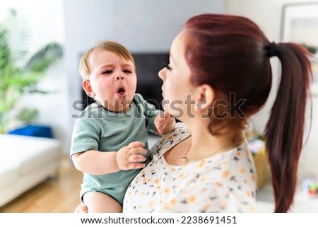 A mother holding child baby on the living room. The baby is sick having some cough Royalty-Free Stock Photo #2238691451