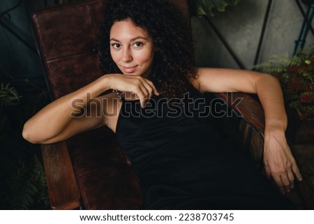 Portrait of a smiling curly woman sitting in a chair. High quality photo