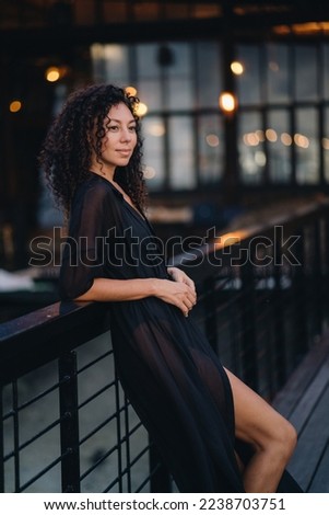 Portrait of a curly woman at dark background with lights. High quality photo