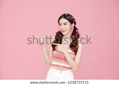 Young beautiful Asian happy cute slim woman with pigtails and perfect skin having fun and posing on pink isolated background. Stylish female model in studio.