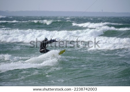 Kitesurfing, riding board waves during storm holding to flying kite