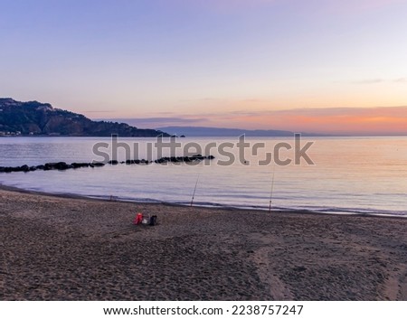 fishing on a sunrise beach in gulf with surf , calm water and beautiful clouds on a background of a sea landscape
