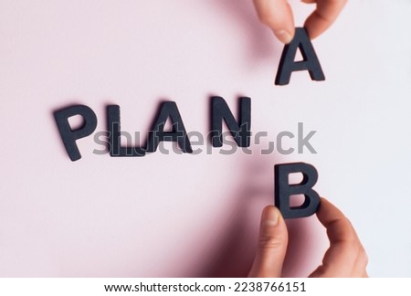 Top view of the scattered letters and the inscription, folded into the words "plan a", the hands of people replace the letter a with b. Creative concept about plan b, strategies and opportunities.