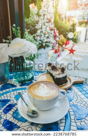 Merry x-mas,Hot coffee latte with latte art milk foam in cup mug and Homemade chocolate cake with Xmas decors and Xmas tree baubles on marble floor desk Celebrating Merry Christmas and New year.