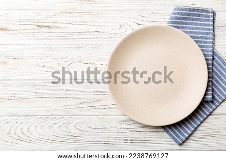 Top view on colored background empty round white plate on tablecloth for food. Empty dish on napkin with space for your design. Royalty-Free Stock Photo #2238769127