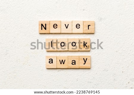 Never look away word written on wood block. Never look away text on cement table for your desing, concept.