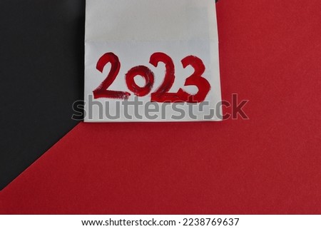red inscription 2023 on white paper on red black background