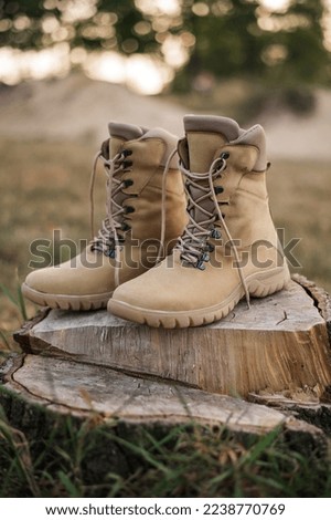 High-top lace-up sneakers in military paint on the sand. Tactical army specialized sneakers for field conditions