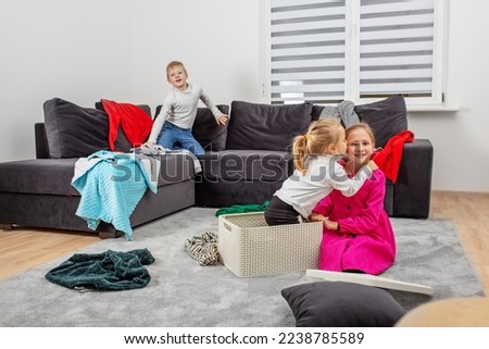 Three children are having fun in room and making mess. Happy childhood. Family concept. Scattered clothes