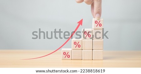 Financial interest rate and mortgage interest rate, hand holding wooden block with percentage icon and arrow pointing up, economy is improving