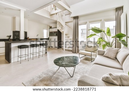 a living room with couchs, chairs and a coffee table in the center of the room is an open kitchen Royalty-Free Stock Photo #2238818771