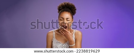 Tired attractive african-american party girl. had fun night yawning sleepy close eyes cover opened mouth tired standing exhausted in silver trendy dress wake up early standing blue background.