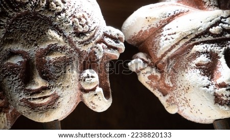 two face sculptures showing one woman and the other man made of stone. Both were typically wearing balinese headcap over a dark background Royalty-Free Stock Photo #2238820133