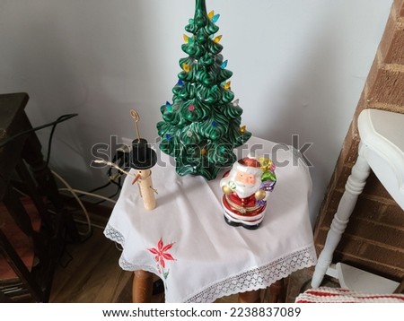 A Santa, Snowman, and tree ornament setup on a small table for decoration.