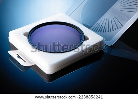 neutral gray lens filter on black glass in protective case, blue backlight