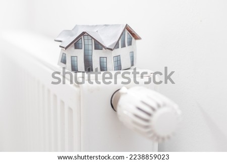 A toy house lie on the radiator of the heating system, heating, housing, fuel crisis.