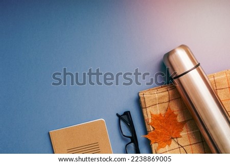 Creative Top view flat lay outdoors trip composition. Thermos blanket autumn leaf grey blue background copy space. Template weekend outing picnic nature tourism recreation